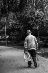 Oudere man met een wandelstok loopt op een weggetje